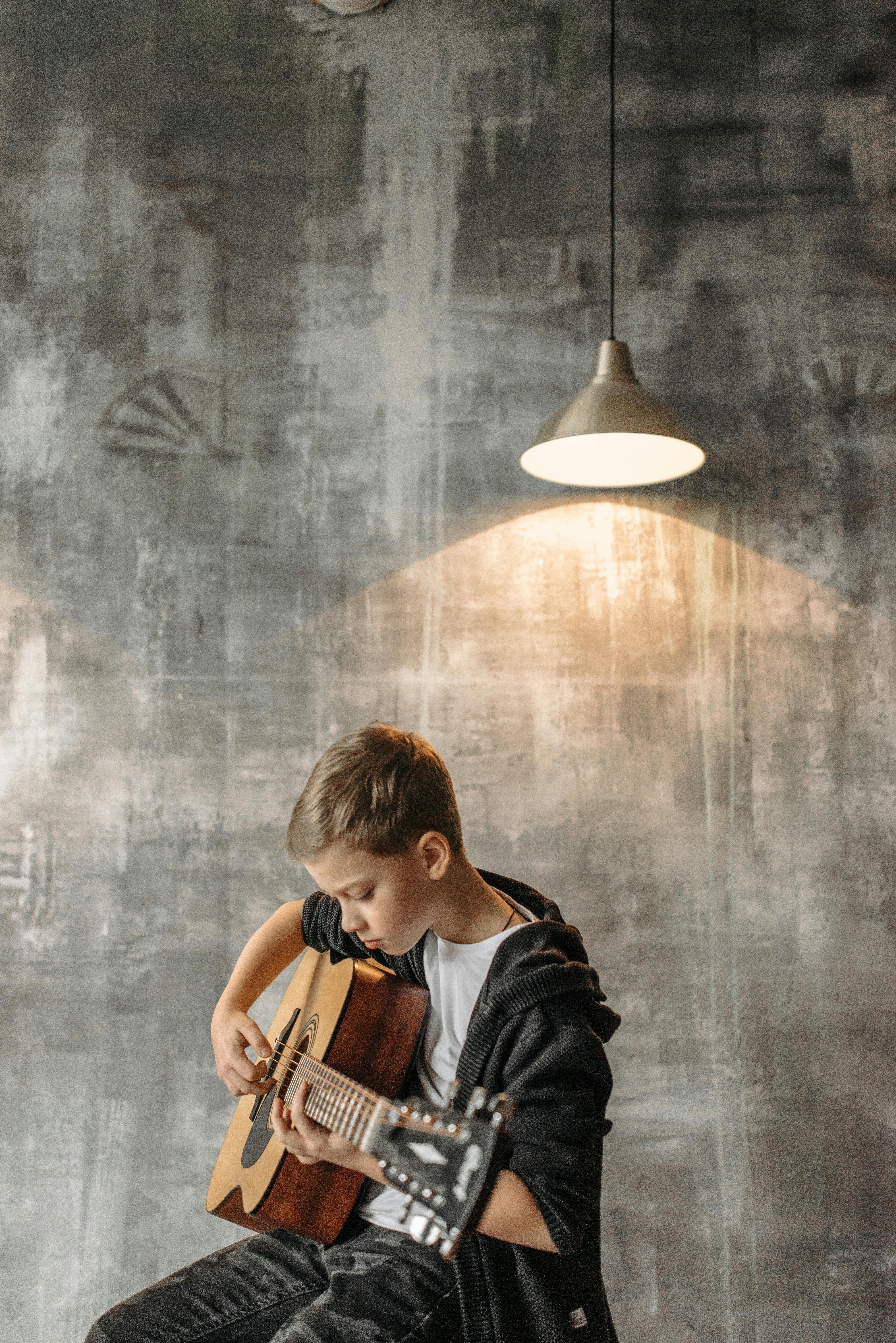 kid around 12 years old playing a acoustic guitar